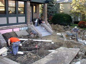 Plumber trenches for downspout, Dave and Linda prep steps, and Cruz muds sump. Trench to city storm sewer is in background.