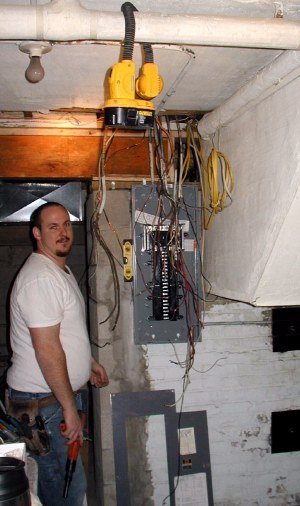 In a dark basement, Frank Mikolajczyk starts to rewire the main circuit panel